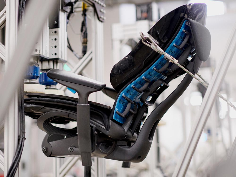 Een Embody Gaming Chair, vanaf de zijkant gezien, in een testmachine op de productielocatie van Herman Miller.