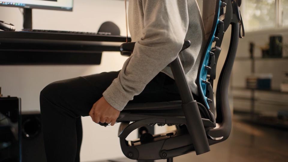 Een close-up video van de zijkant van een zwarte Embody Gaming Chair verstelbaar zitdiepte mechanisme dat wordt ingesteld door een persoon in een trui en broek.